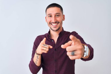 Genç yakışıklı iş adamı izole edilmiş arka planda durmuş mutlu ve komik yüzlü parmakları kameraya doğrultuyor. İyi enerji ve titreşimler.