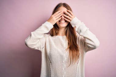 Genç, güzel, kızıl saçlı bir kadın pembe arka planda gözlük takıyor. Gözleri kapatıyordu. Neşeli ve komik gülümsüyordu. Kör kavram.