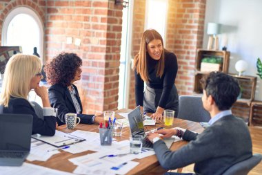 Bir grup iş adamı mutlu ve kendinden emin gülümsüyor. Yüzünde gülümsemeyle birlikte çalışmak. Genç ve güzel bir kadın büroda belgeleri açıklıyor.