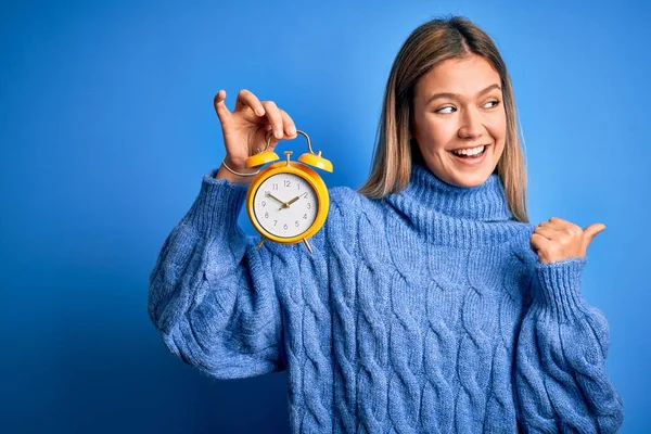 Jovem Bela Mulher Segurando Despertador Sobre Fundo Azul Isolado Apontando — Fotografia de Stock