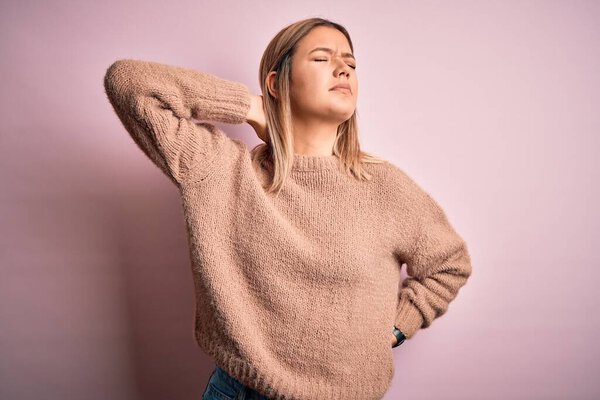 Young beautiful blonde woman wearing winter wool sweater over pink isolated background Suffering of neck ache injury, touching neck with hand, muscular pain