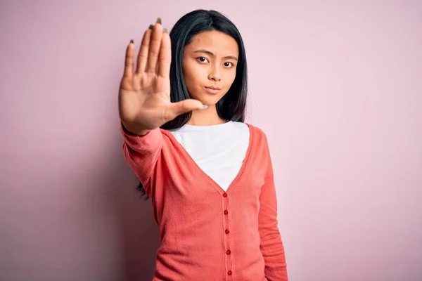 年轻美丽的中国女人穿着休闲装 披着孤立的粉色背景 手牵着手唱着歌 脸上带有消极而严肃的手势的警告表情 — 图库照片