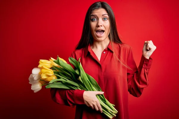 Young beautiful romantic woman with blue eyes holding beauty bouquet of yellow tulips screaming proud and celebrating victory and success very excited, cheering emotion — Stock Image Young Beautiful Romantic Woman Blue Eyes Holding Beauty Bouquet Yellow Stock Photo