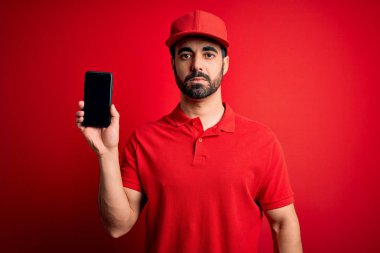 Sakallı, akıllı telefonlu yakışıklı teslimatçı akıllı yüzlü, ciddi düşünen, kendinden emin bir ifadeyle yemek uygulaması sunuyor.