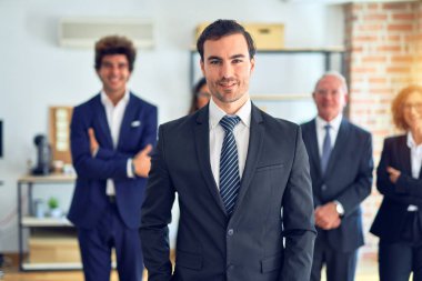 Bir grup iş adamı toplantıda mutlu ve kendinden emin gülümsüyor. Yüzünde gülümsemeyle büroda kameraya bakarken..