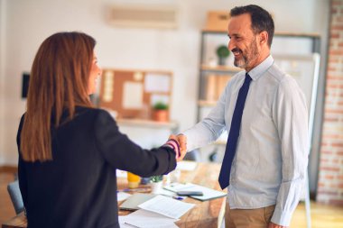 Mutlu ve kendinden emin gülümseyen iki orta yaşlı iş adamı. Yüzünde bir gülümsemeyle ofiste el sallayarak çalışmak.