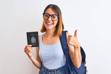 Güzel, kızıl saçlı, sırt çantası takan ve elinde Kanada pasaportu olan güzel bir kız. Gülümseyerek mutlu. Tamam, başparmağını parmaklarınla kaldır.
