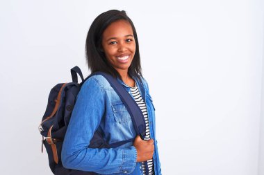 Sırt çantasıyla gezen genç Afrikalı Amerikalı bir bayan mutlu bir yüzü olan, kendine güvenen bir gülümsemeyle dişlerini gösteren.