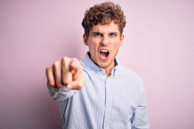 Sarışın, kıvırcık saçlı, beyaz arka planda çizgili tişört giyen genç ve yakışıklı bir adam. Kameraya kızgın ve sinirli olduğunu gösteriyor.