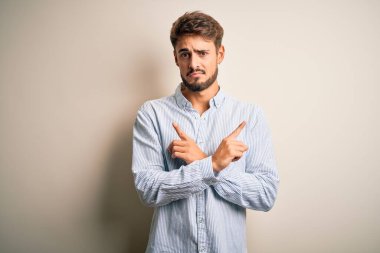 Beyaz arka planda duran çizgili tişörtlü, sakallı genç yakışıklı adam iki tarafı da işaret ediyor, farklı yönler farklı.