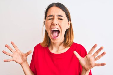 Güzel kızıl saçlı kadın, izole edilmiş arka plan üzerine gündelik kırmızı tişört giyip kollarını kaldırıp heyecanla haykırarak başarının çılgınlığını kutluyor. Kazanan konsept