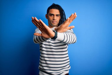 Rastgele çizgili süveter giyen Afro-Amerikan genç, yakışıklı Afro adam. Reddedilmiş yüz ifadesi, olumsuz işaretler, kızgın yüz ifadesi.