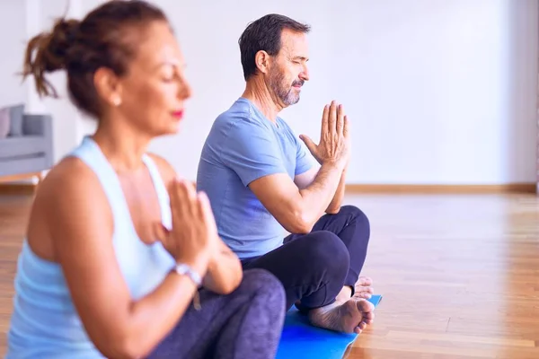 中年漂亮的运动型夫妇坐在垫子上练习瑜伽 在体育馆里做祷告 — 图库照片
