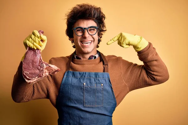 Homem Carniceiro Bonito Jovem Segurando Atender Bife Sobre Fundo Amarelo — Fotografia de Stock