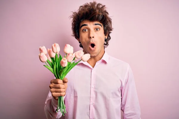 Mladý Pohledný Muž Drží Květiny Stojící Nad Izolovaným Růžovým Pozadím — Stock fotografie