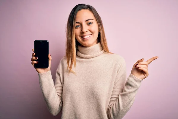 Młoda Piękna Brunetka Kobieta Trzyma Smartfon Pokazując Ekran Różowym Tle — Zdjęcie stockowe