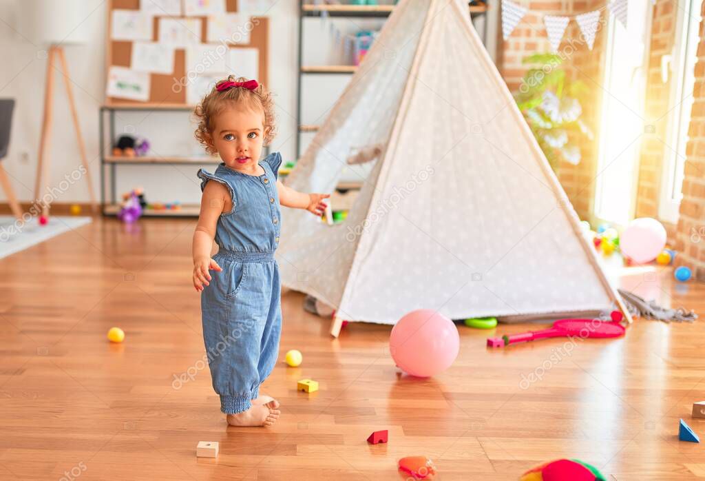 Beautiful caucasian infant playing with toys at colorful playroom. Happy and playful with pink baloon at kindergarten.