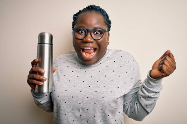 Genç Afro-Amerikan, saçları örgülü, termosu olan, elinde kahveyle gururla bağıran, zaferi ve başarıyı kutlayan heyecanlı, coşkulu, neşeli bir kadın.