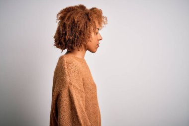 Kıvırcık saçlı, sıradan bir süveter giyen, rahat bir profil pozu veren, kendine güvenen gülümseyen güzel Afro-Amerikan kadın..