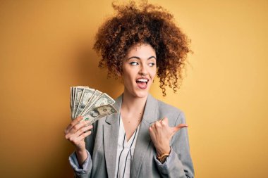 Kıvırcık saçlı, piercingli, dolarlar tutan genç ve güzel bir kadın.