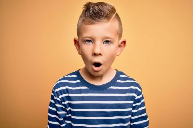 Mavi gözlü, sarı arka planda deniz çizgili tişört giyen küçük beyaz çocuk korku, şaşkınlık ifadesi ve heyecanlı yüz ifadesiyle dehşete düşmüş ve şok olmuştu..