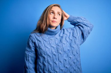 Mavi arkaplan üzerine balıkçı yaka kazak giyen genç, güzel sarışın kadın soru sormayı merak ediyor. Şüpheyle kararsız, kafa kafaya düşünerek. Düşünceli kavram.