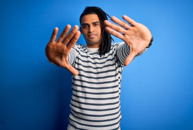 Rastgele çizgili süveter giyen, el ve parmaklarıyla çerçeve yapan, fotoğraf makinesi perspektifi olan Afro-Amerikan genç yakışıklı adam.