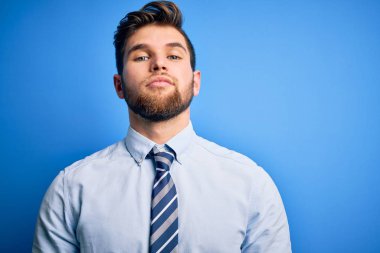Sakallı, mavi gözlü, şık gömlekli ve kravatlı genç sarışın iş adamı yüzünde ciddi bir ifadeyle rahatlamış duruyor. Basit ve doğal bir şekilde kameraya bakıyorsun..