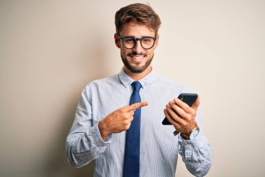 Genç işadamı beyaz arka plan üzerinde akıllı telefon kullanarak konuşuyor. Elle ve parmakla işaret ederek çok mutlu.