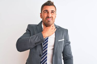 Takım elbiseli ve kravatlı genç yakışıklı bir iş adamı izole edilmiş arka planda acı çeken bir boyuna dokunuyor, grip, mantar ve enfeksiyon yüzünden boğazı ağrıyor.
