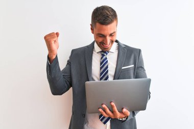 Genç yakışıklı iş adamı bilgisayarını kullanarak izole edilmiş arka planda çalışıyor. Gururla bağırıyor, zaferi ve başarıyı kutluyor. Çok heyecanlı, coşkulu bir duygu.