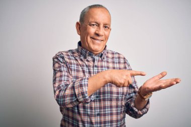 Üst düzey yakışıklı adam, izole edilmiş beyaz arka planda dikilirken kameraya hayret ediyor ve gülümsüyor..