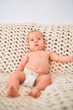 Evdeki battaniyenin üzerinde kanepeye uzanmış sevimli bir bebek. Yeni doğmuş bebek rahatlıyor ve dinleniyor.