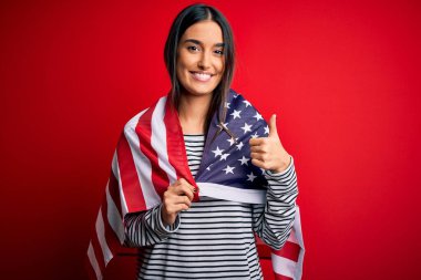 Genç, güzel, vatansever, Amerika Birleşik Devletleri bayrağı taşıyan bir kadın. Büyük bir gülümsemeyle mutlu.