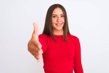 İzole edilmiş beyaz arka planda duran kırmızı günlük tişört giyen genç ve güzel bir kız dostça bir selamlama ve hoş geldin hediyesi olarak el sıkışma sunuyor. Başarılı bir iş..