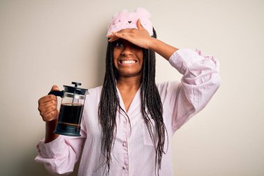 Genç Afro-Amerikalı kadın pijama giyip kahveyi yorgun yapıyor. Kafa kafaya verip strese sokuyor. Utanç ve şaşkınlık dolu bir yüz ifadesi var. Hata için korku ve üzüntü.