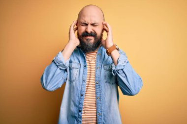 Gürültülü müzik sesi için sakallı, sıradan kot ceket giyen ve kulakları parmaklı çizgili tişört giyen yakışıklı kel bir adam. Sağır kavramı.