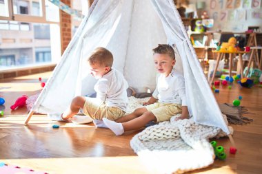 Anaokulunda bir sürü oyuncağın etrafında oynayan sevimli sarışın ikizler.