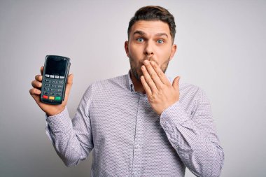Mavi gözlü genç iş adamı, veri bankası ödeme terminalini izole edilmiş arka planda tutuyordu. Ağzı, hata üstüne utançla kaplıydı. Korkunun ifadesi, sessizlikten korkmak, gizli konsept.