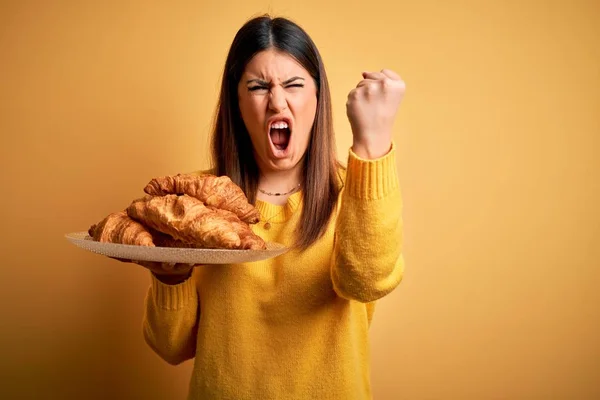 Young Beautiful Woman Holding French Croissant Pastry Yellow Background Annoyed — Stock Photo, Image