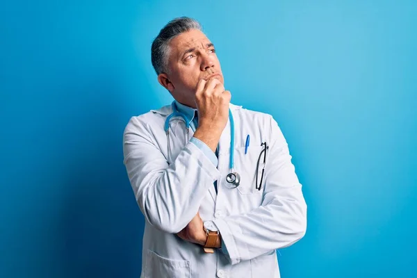 Średnim Wieku Przystojny Siwowłosy Lekarz Płaszczu Niebieskim Stetoskopie Ręką Podbródku — Zdjęcie stockowe