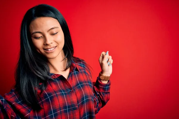 若い美しい中国人女性を身に着けているカジュアルシャツ上隔離された赤の背景ダンス幸せと陽気 笑顔移動カジュアルと自信を持って音楽を聴く — ストック写真