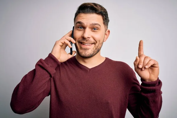 スマートフォンで会話をしている青い目の若者が 幸せな顔をした指を指差すアイデアや質問に驚き ナンバー1 — ストック写真