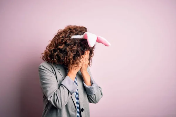 泣きながら手で顔を覆う悲しい表情で孤立したピンクの背景の上に立っているウサギの耳を身に着けている中世の美しい女性 うつ病の概念 — ストック写真