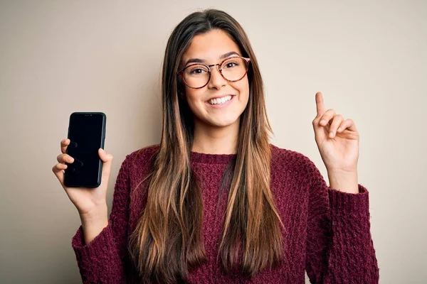 Menina Bonita Nova Usando Óculos Mostrando Smartphone Sobre Fundo Branco — Fotografia de Stock