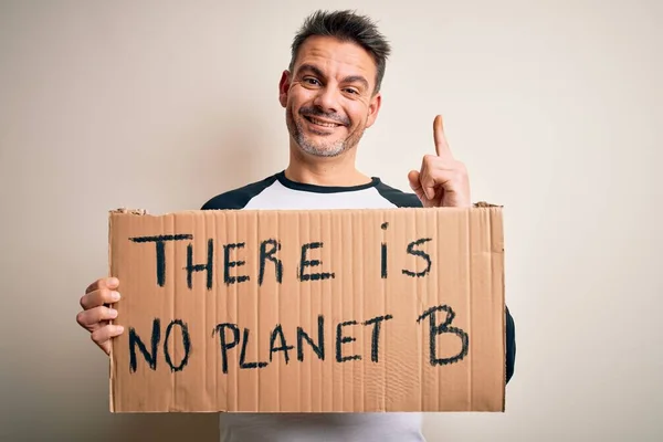 Young handsome man asking for environment holding banner with planet message surprised with an idea or question pointing finger with happy face, number one