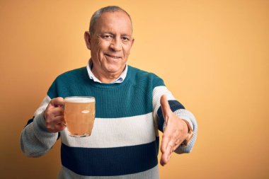 Üst düzey yakışıklı adam izole edilmiş sarı arka planda duran bira kavanozunu içerken dostça bir selamlama ve hoş geldin hediyesi olarak gülümsedi. Başarılı bir iş..