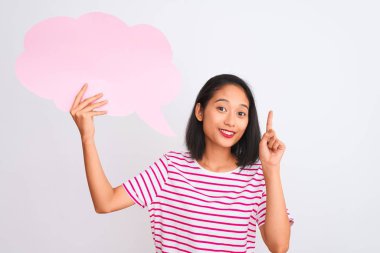 Genç Çinli bir kadın bulutlu konuşma baloncuğu tutuyor. İzole edilmiş beyaz arka planda duruyor. Bir fikir ya da soru işareti ile şaşırıyor.