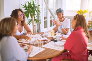 Genç ve güzel bir kız mutlu ve kendinden emin bir şekilde terasta oturmuş bir fincan kahve içiyor.