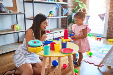 Genç, güzel öğretmen ve bebek, anaokulundaki masada halkalar kullanarak piramit inşa ediyorlar.